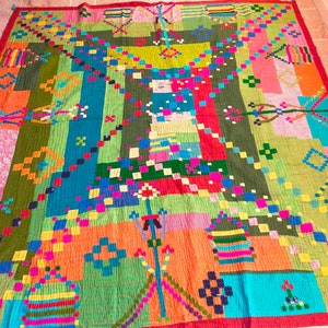May include: A colorful patchwork quilt with geometric patterns in shades of red, orange, green, blue, pink, and yellow. The quilt is made of different fabrics sewn together to create a unique and vibrant design.