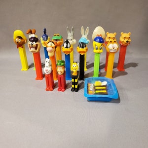 May include: A collection of 14 colorful cartoon character themed plastic pencil toppers. The toppers feature characters like Tweety Bird, Bugs Bunny, Taz, and more.