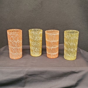 May include: Four clear glass tumblers with a yellow and orange ombre effect and a white geometric pattern.