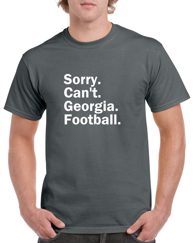Puede incluir: Una camiseta gris oscuro con texto blanco que dice "Lo siento. No puedo. Georgia. F&uacute;tbol."