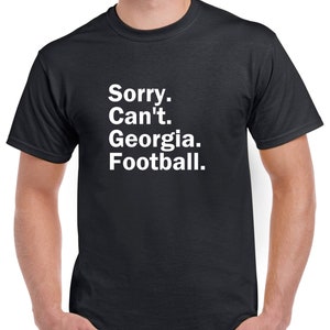 Puede incluir: Una camiseta negra con texto blanco que dice "Lo siento. No puedo. Georgia. F&uacute;tbol."