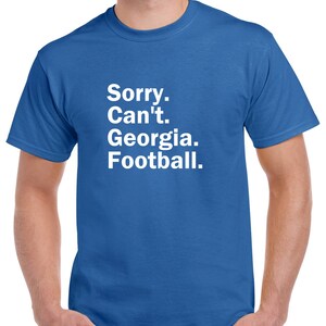 Puede incluir: Una camiseta azul real con texto blanco que dice "Lo siento. No puedo. Georgia. F&uacute;tbol."