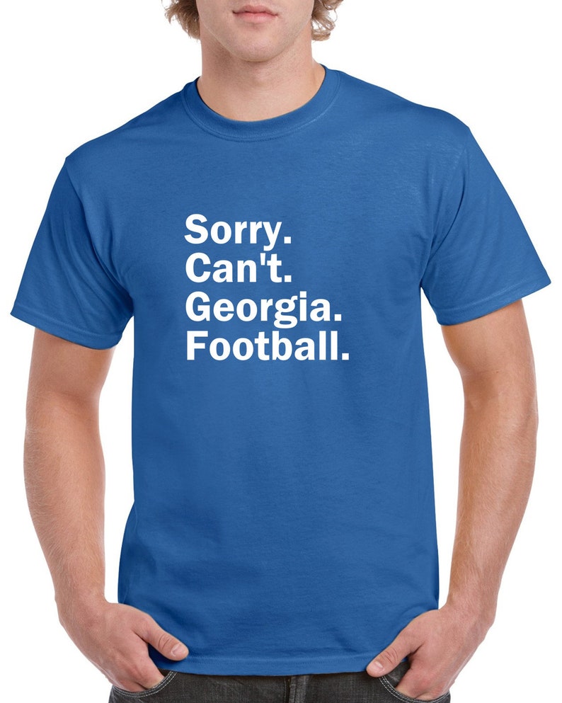 Puede incluir: Una camiseta azul real con texto blanco que dice "Lo siento. No puedo. Georgia. F&uacute;tbol."