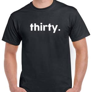 Puede incluir: Una camiseta negra con la palabra "thirty." impresa en blanco en la parte delantera.