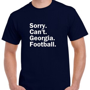 Puede incluir: Una camiseta azul marino con texto blanco que dice "Lo siento. No puedo. Georgia. F&uacute;tbol."