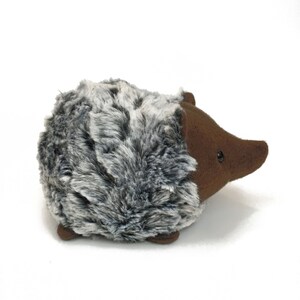 May include: A plush brown and gray hedgehog toy with a furry body and a brown snout.