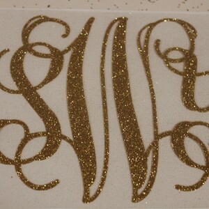 May include: Gold glitter monogram with the letters S, M, and Y in a cursive script font.
