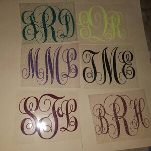 May include: Six different monogram designs on a white background. The monograms are made of glitter and are in different colors, including green, yellow, purple, black, and maroon.
