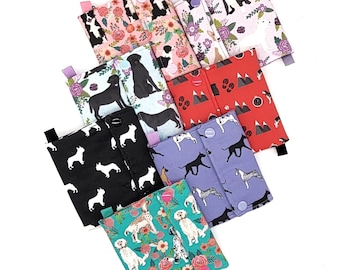 May include: Six different fabric pouches with various dog breed patterns. The pouches are made of a soft, quilted fabric and have a snap closure. The patterns include floral, mountain, and dog breeds.
