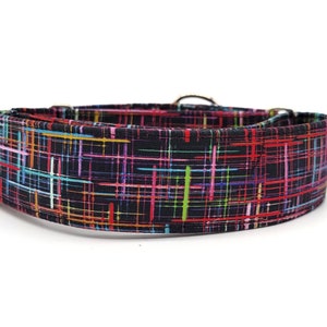 May include: A black dog collar with a colorful plaid pattern. The collar has silver hardware and is made of durable fabric.