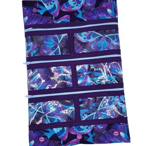 May include: Purple zippered pouch with clear plastic pockets and a butterfly print. The pouch has multiple compartments and is perfect for organizing small items.