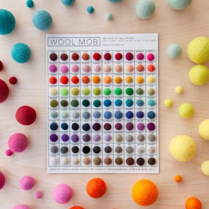 May include: A color chart of 100% wool felt balls in various sizes and colors. The chart is labeled "Wool Mob" and includes the sizes 1 cm, 2 cm, 3 cm, 4 cm, 6 cm, 7 cm, and 8 cm. The felt balls are arranged in rows and columns, with each color having a corresponding name.
