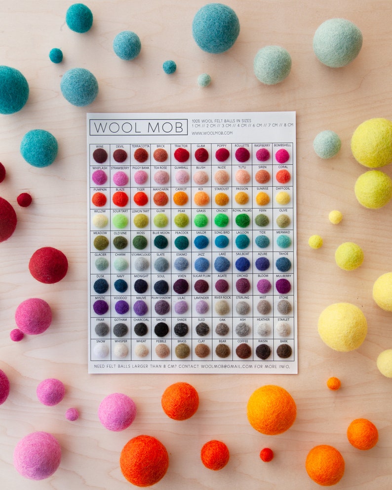 May include: A color chart of 100% wool felt balls in various sizes and colors. The chart is labeled "Wool Mob" and includes the sizes 1 cm, 2 cm, 3 cm, 4 cm, 6 cm, 7 cm, and 8 cm. The felt balls are arranged in rows and columns, with each color having a corresponding name.