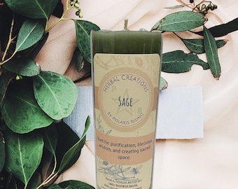 May include: A green candle with a label that reads "Herbal Creations Sage by Polaris Rising". The label also says "Used for purification, blessings, wisdom, and creating sacred space."