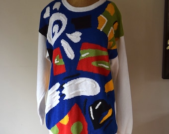 May include: A white sweater with a colourful abstract design. The design features blue, red, yellow, green and black shapes.