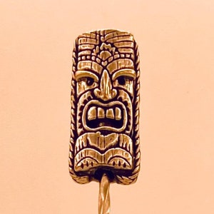 May include: A gold tiki-shaped cocktail stirrer with a twisted handle.