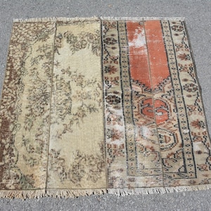 Könnte beinhalten: Ein Vintage-Teppich mit einem verblassten Farbton in Orange, Braun und Creme. Der Teppich hat ein geometrisches Muster und einen Fransenrand.