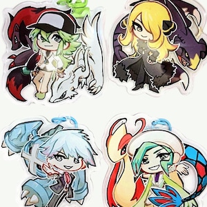 Puede incluir: Cuatro llaveros coloridos con personajes de estilo anime de la franquicia Pokémon. Cada llavero presenta un personaje y un Pokémon diferentes, incluyendo un entrenador con un Pokémon de pelo verde, un entrenador con un Pokémon de pelo amarillo, un entrenador con un Pokémon de pelo azul y un entrenador con un Pokémon de pelo verde.