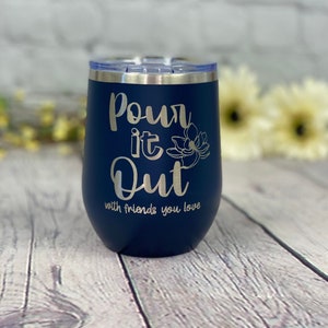 May include: A navy blue stainless steel tumbler with the text "Pour it Out with friends you love" and a floral design.