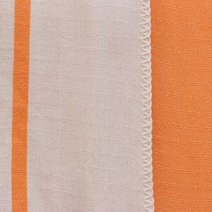 May include: A close-up of a white fabric with a single orange stripe running vertically down the left side. The fabric is sewn to a solid orange fabric.