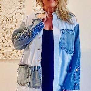 May include: A light blue and white denim shirt with two front pockets and denim sleeves. The shirt has a button-down front and a relaxed fit. The sleeves are a darker shade of blue denim. The shirt is a unique, patchwork design.