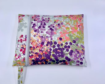 May include: A gray zippered pouch with a floral print featuring purple, pink, and green colors. The pouch has a zipper closure and a pull tab.