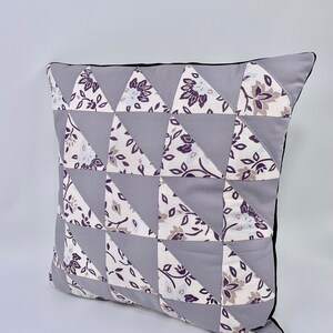 May include: A grey and white patterned cushion with a black trim. The cushion is made of fabric and has a geometric design.