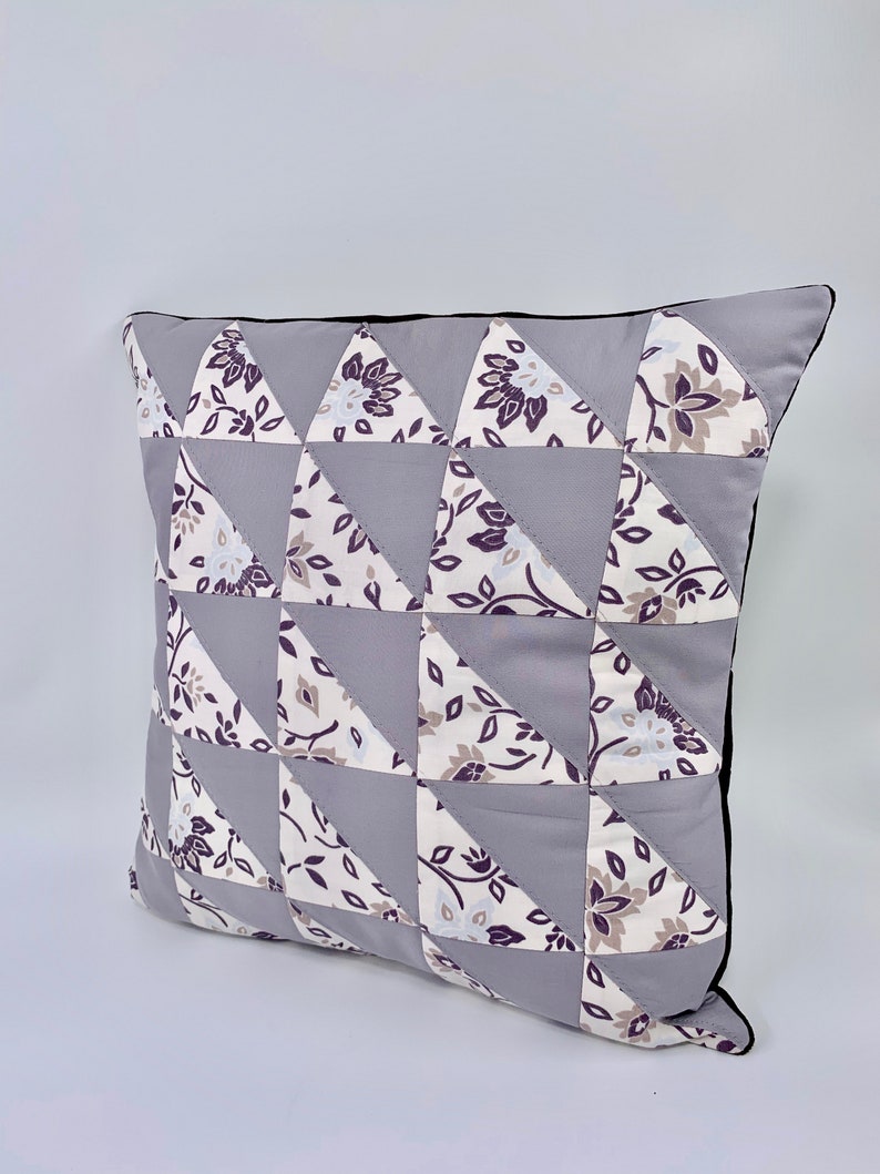 May include: A grey and white patterned cushion with a black trim. The cushion is made of fabric and has a geometric design.