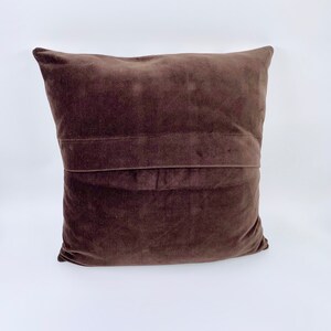 May include: A brown velvet cushion with a seam down the centre.