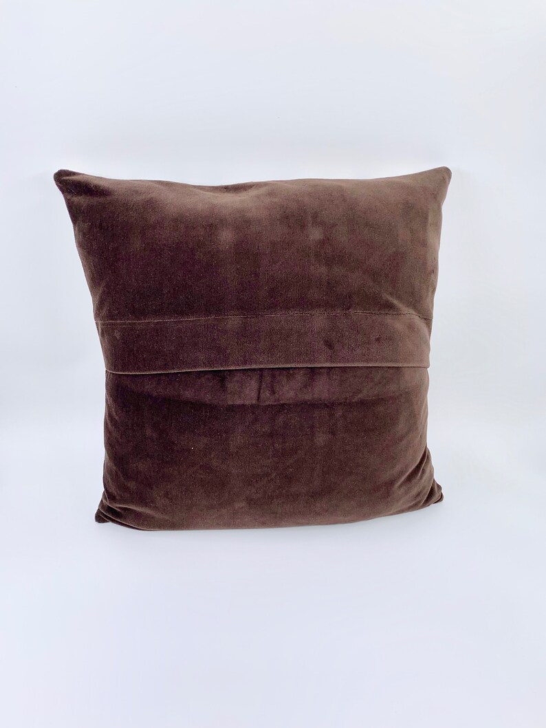 May include: A brown velvet cushion with a seam down the centre.