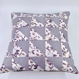 May include: A grey and white patterned pillow with a geometric design. The pillow is made of fabric and has a black trim.