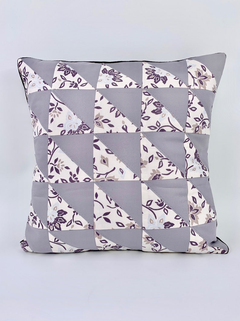 May include: A grey and white patterned cushion with a black trim. The cushion is made of fabric and has a geometric design.