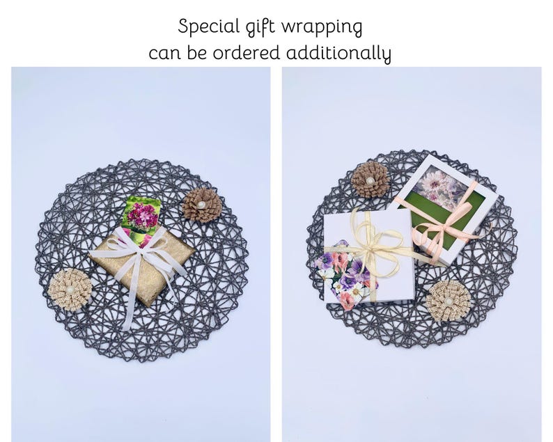 May include: Two gift boxes, one gold and one white, are presented on a dark gray woven placemat. The gold box is tied with a cream ribbon, and the white box has a floral design and a cream ribbon. The text "Special gift wrapping can be ordered additionally" is at the top.
