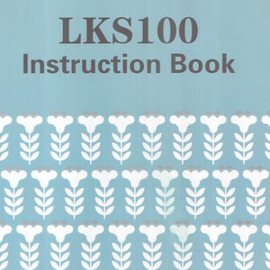 Puede incluir: Un libro de instrucciones con el texto "LKS100 Instruction Book" en letras grises sobre un fondo azul claro. La parte inferior del libro presenta un patrón repetido de flores blancas con acentos grises y tallos verdes.