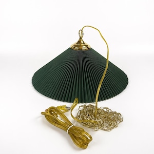 May include: A dark green pleated cone-shaped pendant lamp shade with a polished brass top fixture. The lamp includes a long gold-toned electrical cord and a matching gold-toned metal hanging chain for installation from a ceiling mount.