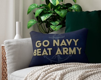 Può includere: Un cuscino blu navy con un'ancora bianca e il testo "Go Navy Beat Army" in lettere dorate.