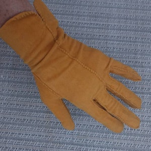 May include: A pair of mustard yellow fabric gloves with a seam down the back of the hand.