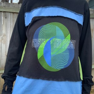 May include: A black long-sleeved shirt with a blue and green graphic design. The graphic features a circle with overlapping lines and the text "Ghosts of the Forest".