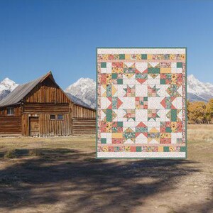May include: A colorful mini quilt pattern with a vintage exploding star design. The finished size is 24 x 28 inches. The quilt features a variety of fabrics in shades of pink, green, yellow, and white. The background includes a rustic wooden building and mountains.