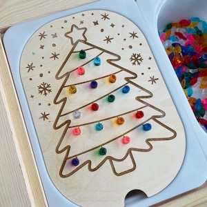 May include: A wooden Christmas tree cutout with a slot for inserting colorful light bulbs. The tree is surrounded by snowflakes and stars. The light bulbs are in a separate container.