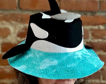 Sombrero para el sol con orca nadando en el océano para niños y adultos. Diversión garantizada y excelente protección solar del verano. Único y exclusivo aquí.