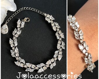 May include: A silver bracelet with a delicate leaf design, featuring clear cubic zirconia stones. The bracelet is shown on a model's wrist.