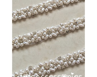 May include: White beaded trim with pearl and rhinestone embellishments. The trim is on a white background.