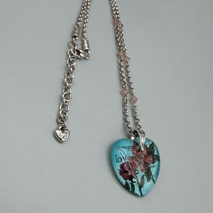 May include: A white ceramic mug with a black handle and the text "But First, Coffee" in a bold, black font. The mug is set against a blurred background, suggesting a cozy setting. The mug appears to be approximately 4 inches tall.