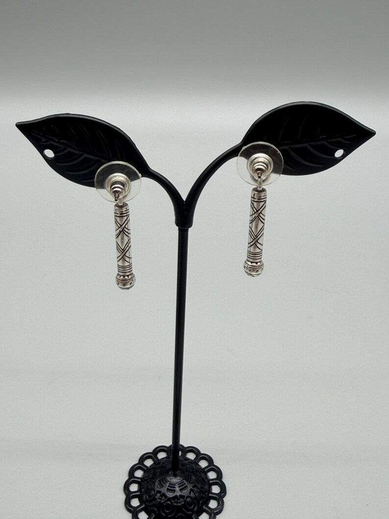 May include: A white ceramic mug with a black handle and the text "But First, Coffee" in a bold, black font. The mug is set against a blurred background, suggesting a cozy setting.