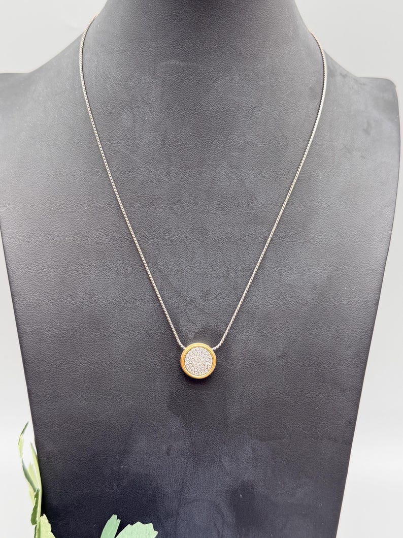 Puede incluir: Una taza de cer&aacute;mica blanca con asa negra y el texto "But First, Coffee" en negrita negra. La taza se encuentra sobre un fondo borroso, sugiriendo un ambiente acogedor.