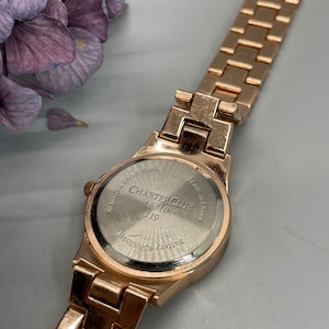 May include: Gold-tone watch with a stainless steel back. The watch face has the text "Charter Club" and "13310/119". The back of the watch says "Stainless Steel Back" and "Made in China".