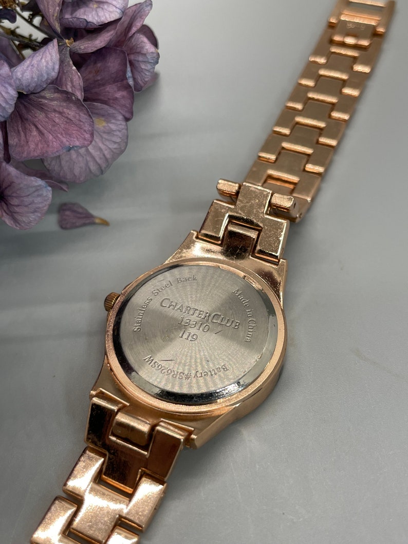 May include: Gold-tone watch with a stainless steel back. The watch face has the text "Charter Club" and "13310/119". The back of the watch says "Stainless Steel Back" and "Made in China".