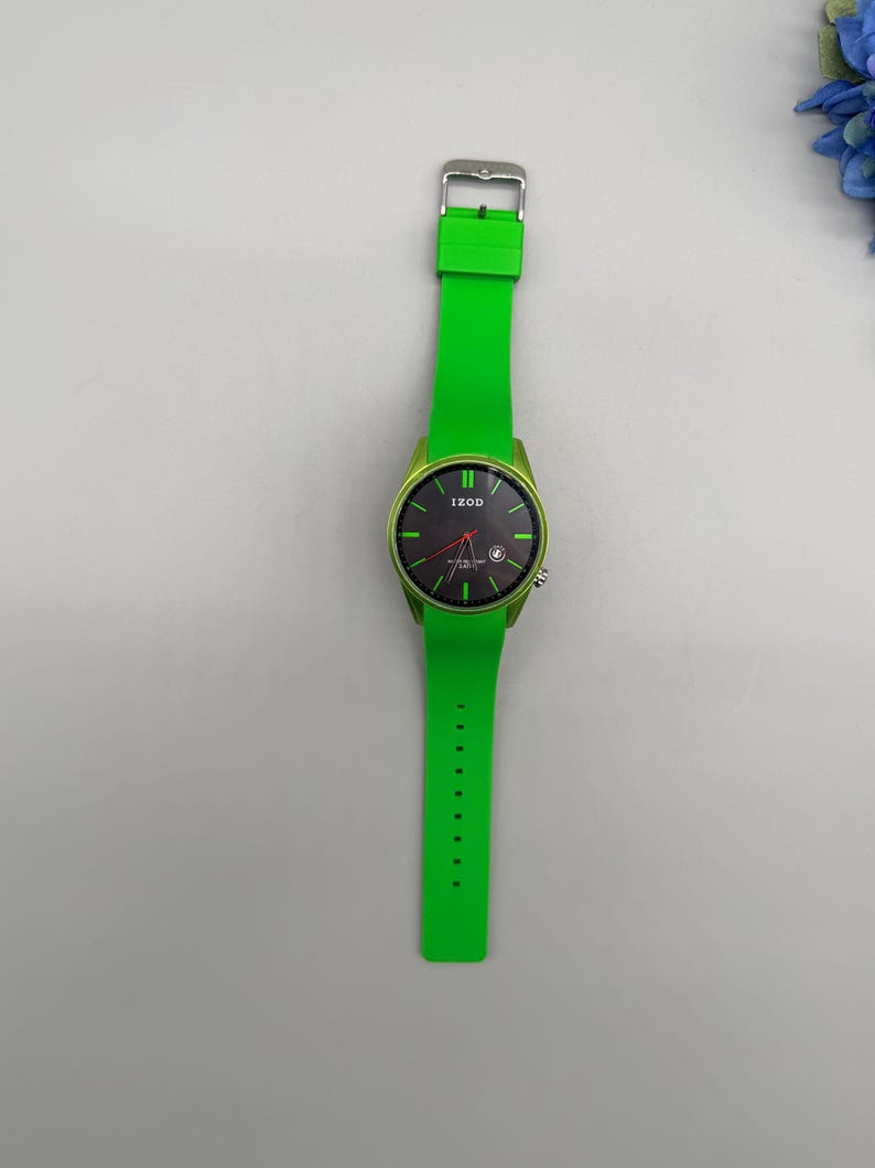 May include: A wristwatch with a bright green silicone strap and a matching green bezel. The round watch face is black with green hour markers, a red second hand, and the brand name IZOD printed in white at the top center of the dial.