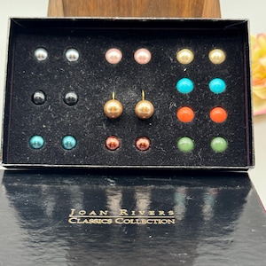 May include: A black box with a variety of colored pearl earrings. The box has the text "JOAN RIVERS CLASSICS COLLECTION" on the front.